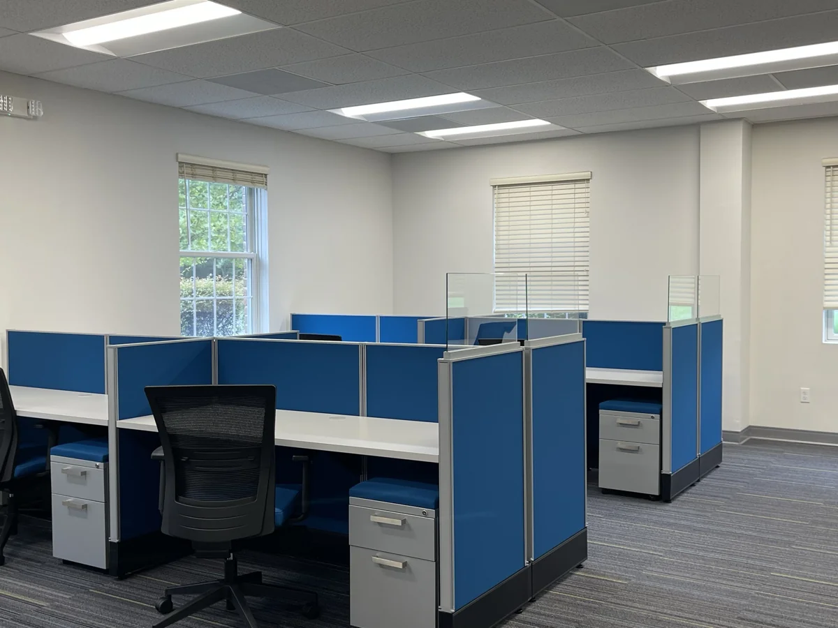 Blue-panel cubicles with black task chairs and under-desk storage